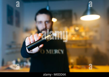 Young man show barbe vaping sur sa main tendue à huis clos. Focus sélectif. Vaping concept. Copier l'espace. Banque D'Images