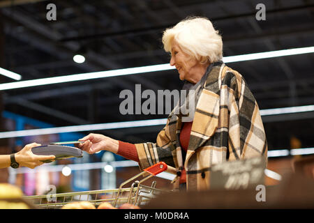 L'aide de NFS Senior Woman in Supermarket Banque D'Images