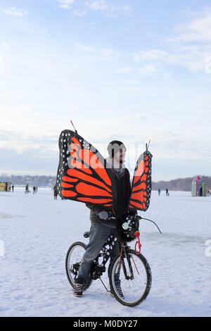 Un homme sur une bicyclette avec des ailes de papillon, à l'Art Shanty Projets sur lac gelé Harriet à Minneapolis, MN, USA. Banque D'Images