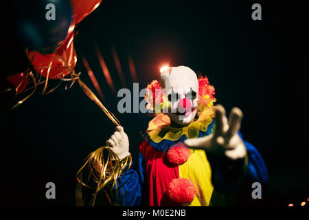 Photo de clown souriant avec des boules dans les mains la nuit Banque D'Images