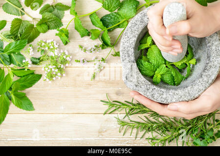 Des herbes fraîches et mortier de pierre sur la planche de bois, vue du dessus Banque D'Images