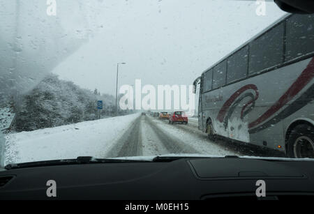 M8, Glasgow, Ecosse, Royaume-Uni, 21 janvier 2018. Conditions de conduite très difficile sur le M8 dans la neige lourde causant des embouteillages depuis longtemps, vu à travers le pare-brise, voiture avec dépassement bus Banque D'Images