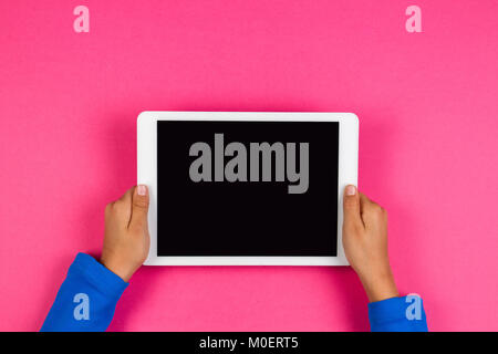 Kid mains avec tablette sur fond rose. Banque D'Images