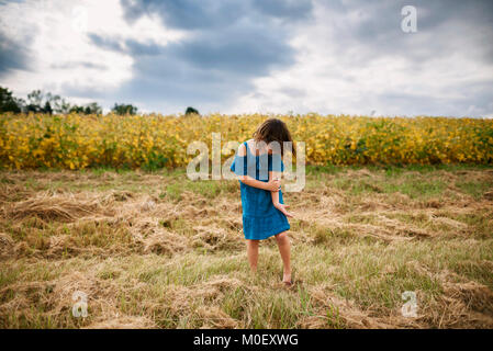 La filature de fille en face d'un champ de soya Banque D'Images