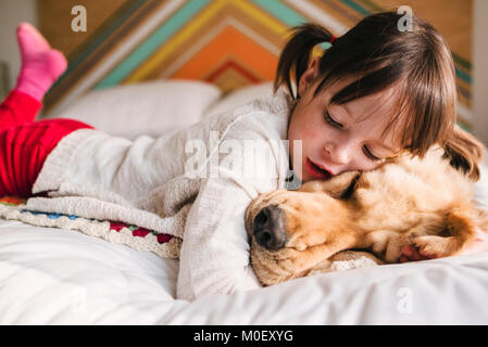 Jeune fille sur un lit avec son golden retriever dog Banque D'Images