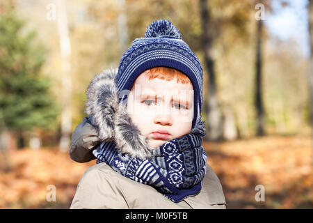 Portrait d'un bel enfant avec une expression contrariée sur le visage. Le garçon est habillé en vêtements chauds, saison d'automne. Gros plan de la photo. Banque D'Images