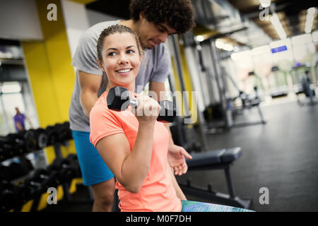 Belle femme faisant des exercices en salle de sport avec un entraîneur personnel Banque D'Images