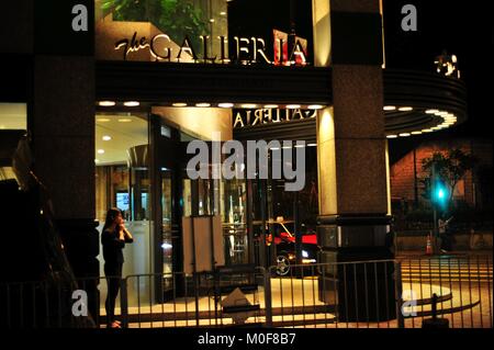 Asian woman fume une cigarette en face d'un centre commercial et est appelé home Banque D'Images