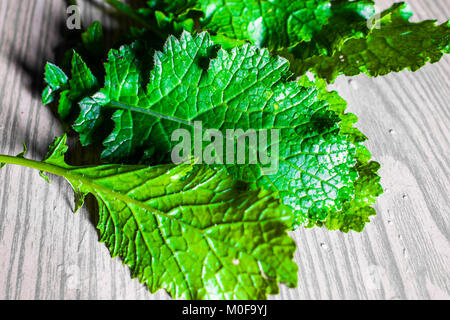 Vue de dessus de la moutarde fraîche et verte feuilles et gouttes d'eau sur eux conservés sur une table en bois Banque D'Images