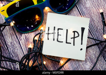 L'aide sur Sticky note papier avec des lunettes de soleil, fond de bois avec des lumières concept pour chercher de l'aide Banque D'Images