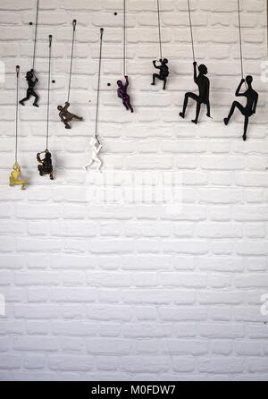 Figurines humaines grimpant sur un mur de briques (concept) Banque D'Images