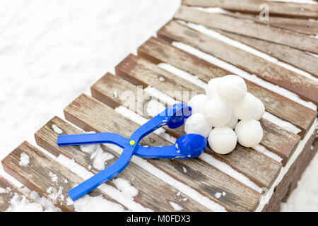 Boule en plastique bleu maker avec ensemble de neige à la pose sur un banc de bois près de l'aire de jeux extérieure pour enfants à journée d'hiver. Banque D'Images