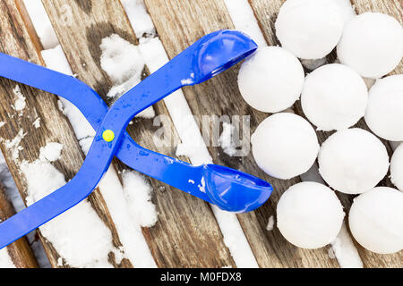 Boule en plastique bleu maker avec ensemble de neige à la pose sur un banc de bois près de l'aire de jeux extérieure pour enfants à journée d'hiver. Banque D'Images