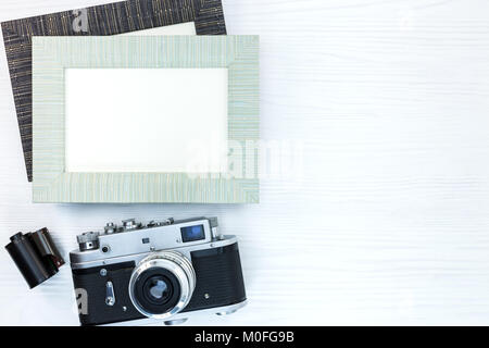 Appareil photo rétro et le rouleau de film et de deux cadres de photo vides sur un bureau en bois blanc Banque D'Images