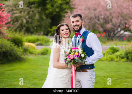 Portrait de jeune couple marié avec juste élégant détails rose sur fond vert nature Banque D'Images