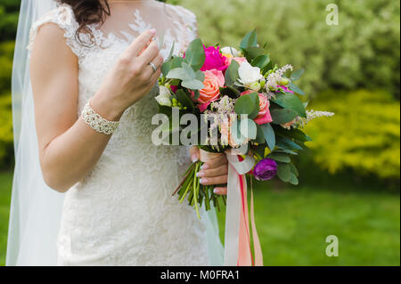 Fragment d'offres juste slim femme mariée avec des bijoux et des fleurs en vert de l'été à l'extérieur d'arrière-plan Banque D'Images