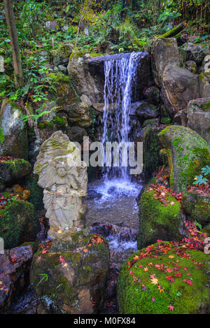 Petite cascade avec statue de Bouddha au jardin d'automne. Banque D'Images