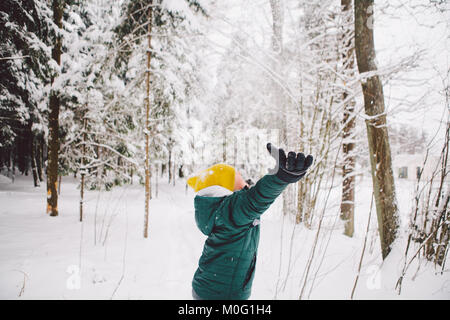 Teenage boy jette des poignées de neige dans l'air et aime de tomber sur son visage. Banque D'Images