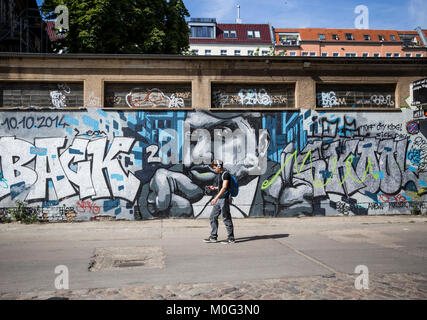 Un homme marche passé à graffiti Urban Spree, Berlin, Allemagne. Banque D'Images