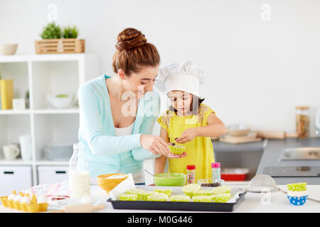 Happy mother and daughter baking cupcakes à la maison Banque D'Images