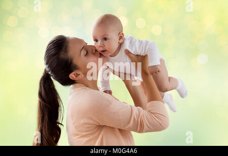 Happy mother kissing little baby boy sur green Banque D'Images