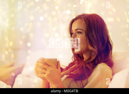 Femme heureuse avec tasse de café au lit à la maison Banque D'Images