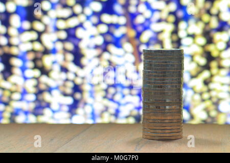 La colonne unique coin pile sur la table de bois avec du jaune de focaliser la lumière sur fond bleu nuit. Pour sauver l'entreprise et de l'argent concept connexe. Banque D'Images