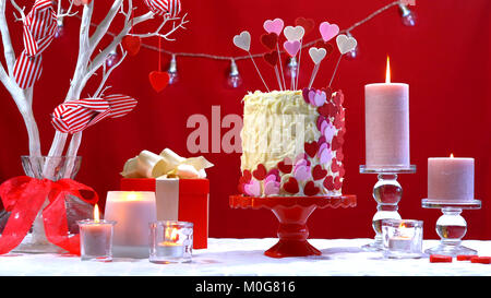 Belle St Valentines Day party table avec showstopper rouge, blanc et coeurs roses gâteau double couche, avec glaçage au chocolat blanc Banque D'Images