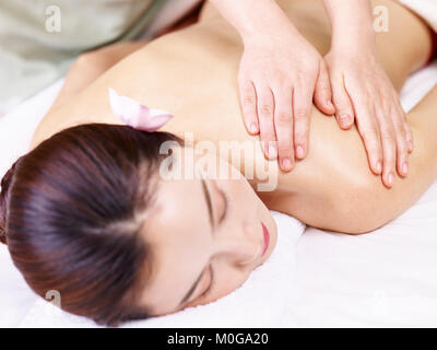 Young Asian woman lying on bed sur avant de recevoir massage in spa salon de coiffure. Banque D'Images