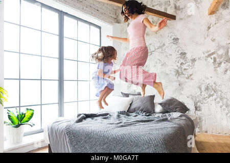 Plaisir en famille. Mère et fille sautant sur le lit Banque D'Images