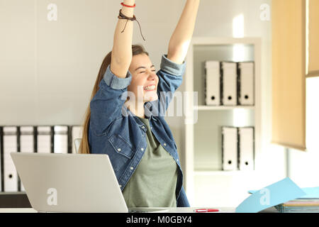 Portrait d'une jeune stagiaire satisfait raising arms at office Banque D'Images