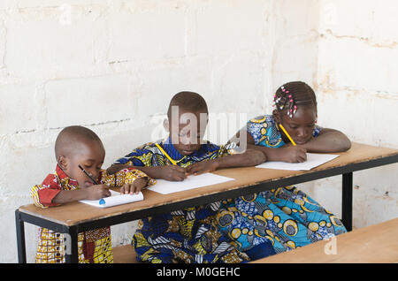 Trois beaux enfants africains à l'école en prenant des notes pendant les cours Banque D'Images