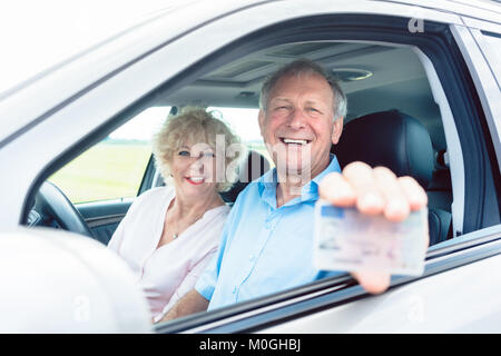 Portrait of a happy man showing his driving license alors que Banque D'Images