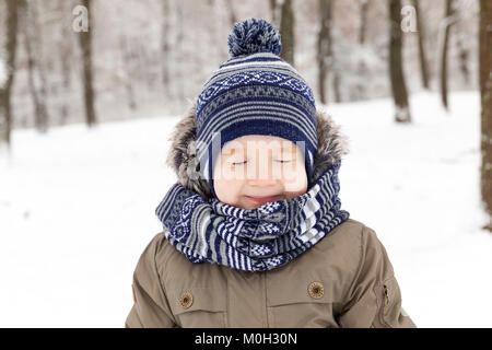 Photo d'un enfant tout en marchant dans un parc d'hiver, close-up portrait. le garçon est habillé en vêtements chauds et loucha Banque D'Images