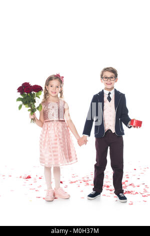 Adorable enfants heureux avec des roses en forme de cœur et boîte-cadeau holding hands and smiling at camera on white Banque D'Images