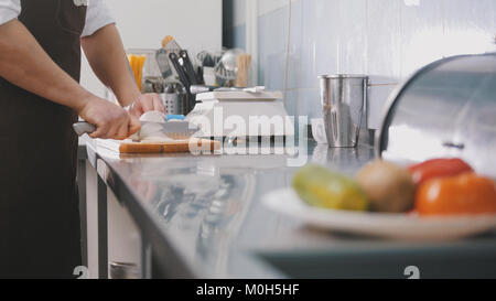 Male chef preparing salad in commercial kitchen - coupe l'oignon Banque D'Images