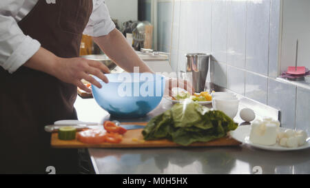 Male chef preparing salad dans la cuisine Banque D'Images