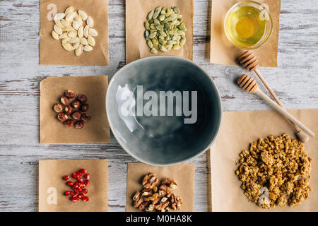 Vue de dessus de muesli ingrédients sur le papier sulfurisé et pièces bol sur la table Banque D'Images