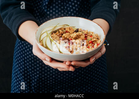 Portrait de femme cuisinière holding bowl avec muesli in hands Banque D'Images