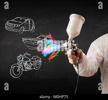 L'homme à l'aérographe peinture en aérosol avec voiture, moto et bateau dessin sur fond sombre Banque D'Images
