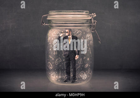 L'homme d'affaires capturé dans un bocal en verre avec à la main des icônes média concept sur arrière-plan Banque D'Images