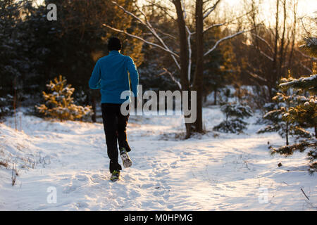 Photo de l'arrière de la jeune athlète qui traverse la forêt d'hiver Banque D'Images