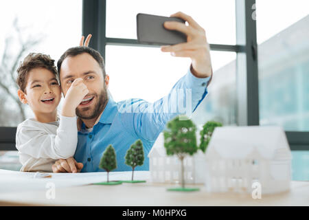 Petit garçon de jouer tout en prenant avec le père selfies Banque D'Images