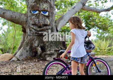 Jeune fille à l'écoute de Billy le bombax tree, Anderson Park Botanic Gardens, Townsville, Queensland, Australie Banque D'Images