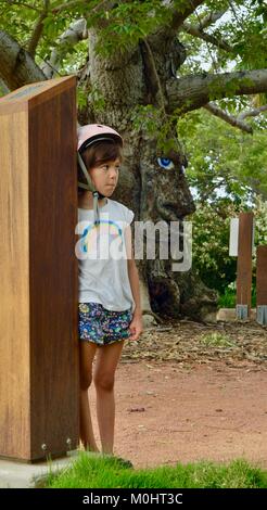 Jeune fille à l'écoute de Billy le bombax tree, Anderson Park Botanic Gardens, Townsville, Queensland, Australie Banque D'Images