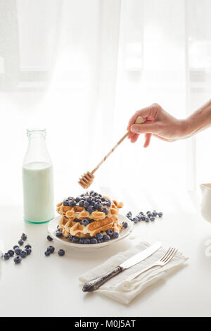 Cropped shot of woman pouring honey sur delicious gaufres Banque D'Images