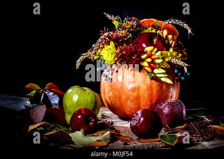 Arrangement de fleurs dans un potiron. Nature morte avec une citrouille, fleurs et les pommes. Banque D'Images