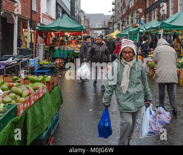 Une vieille dame sacs lourds transporteurs plein de shopping par Surrey Street Market dans la région de Croydon, au sud de Londres. Banque D'Images