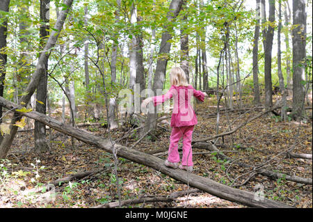 Une fille blonde marche sur un journal dans les bois Banque D'Images