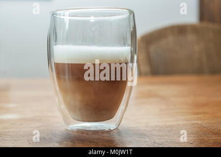 Une vitre avec un latte machiato sur une table en bois en close up Banque D'Images
